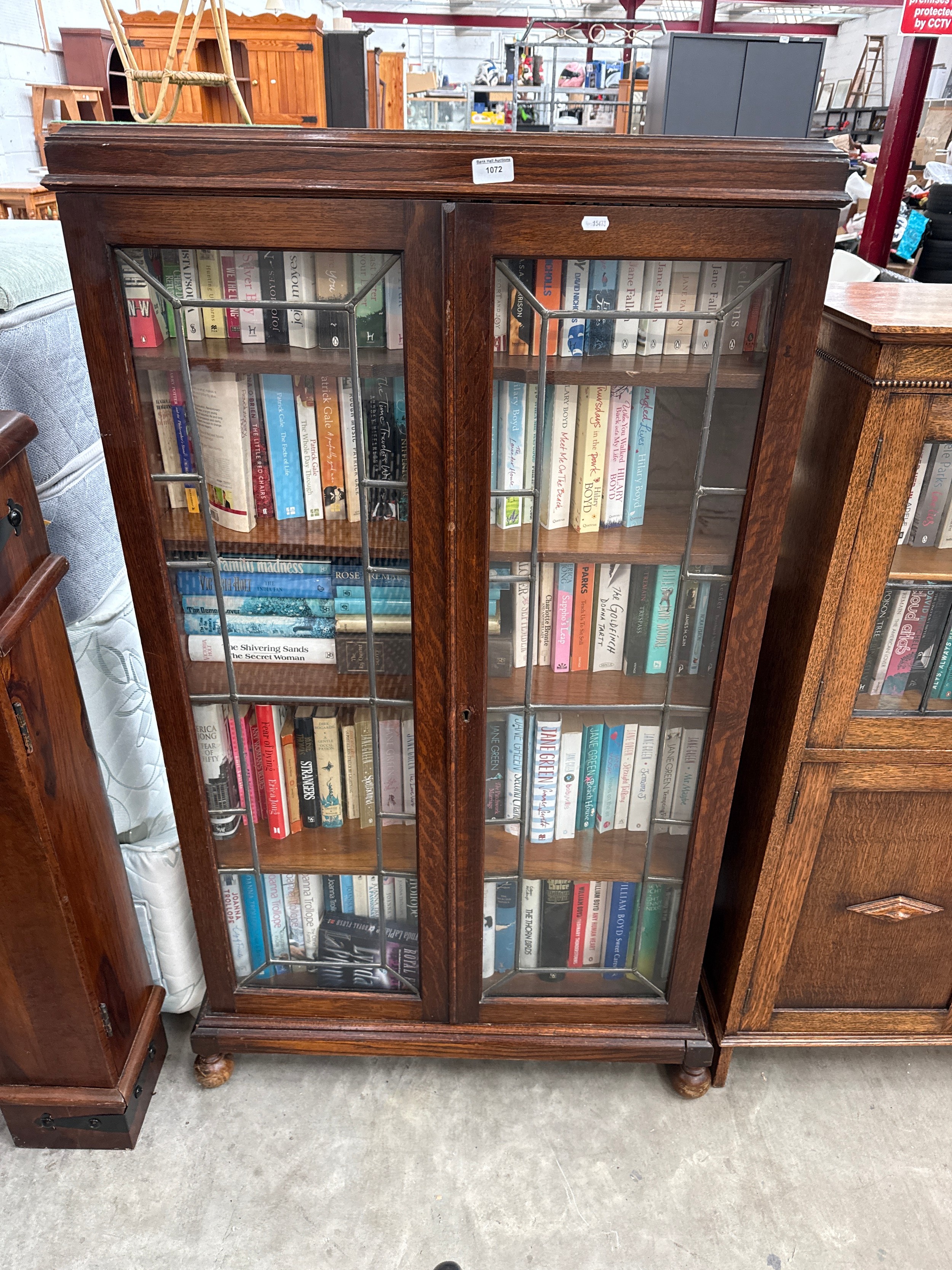 A vintage lead glazed oak 2 door bookcase with contents