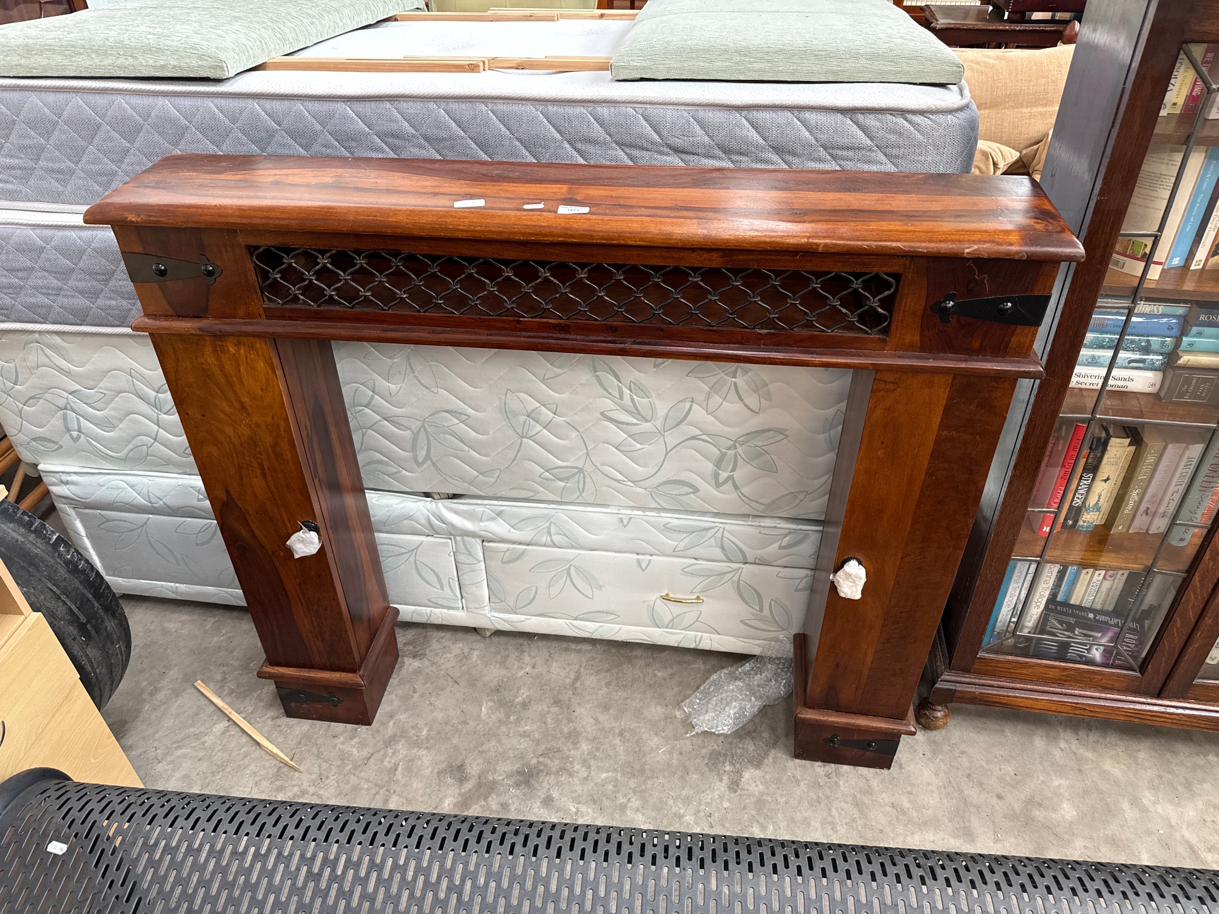 A large Sheesham style hardwood fire surround with side storage towers