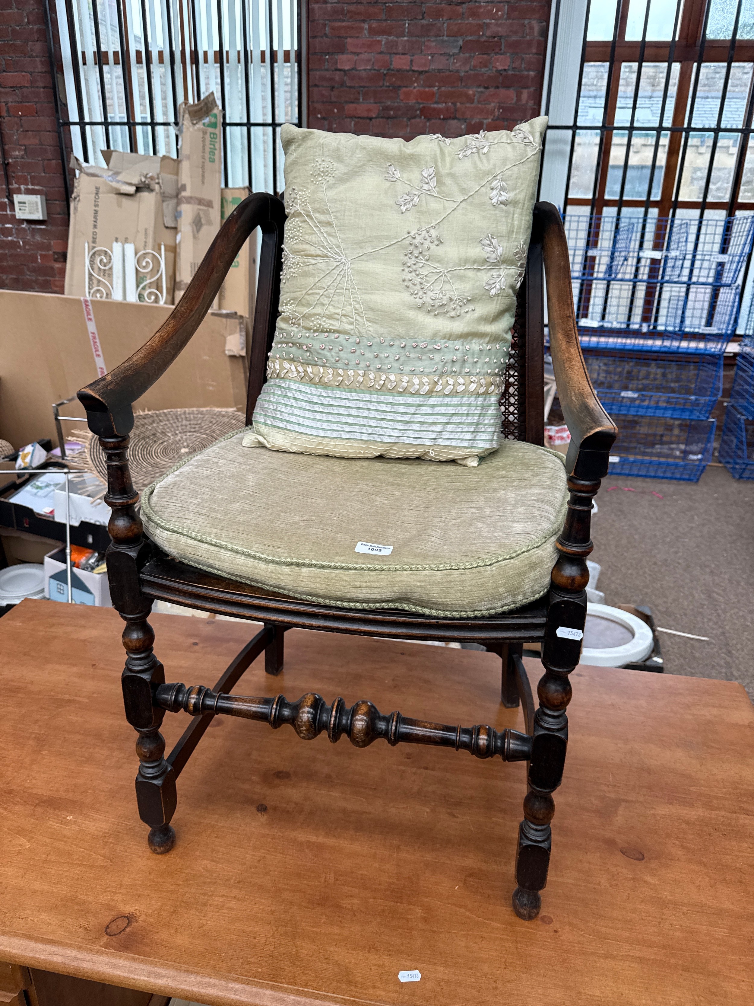 An antique rattan seated elbow chair with bobbin turned frame, with cushions
