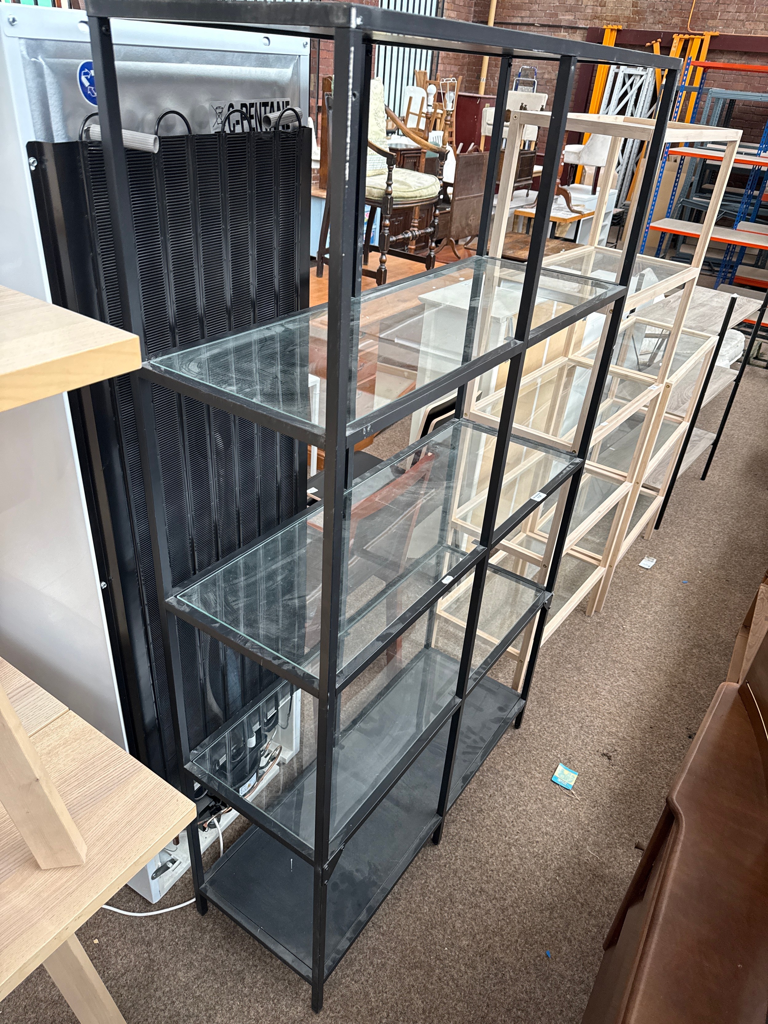 A large metal framed 5 tier open shelf stand with glass shelves