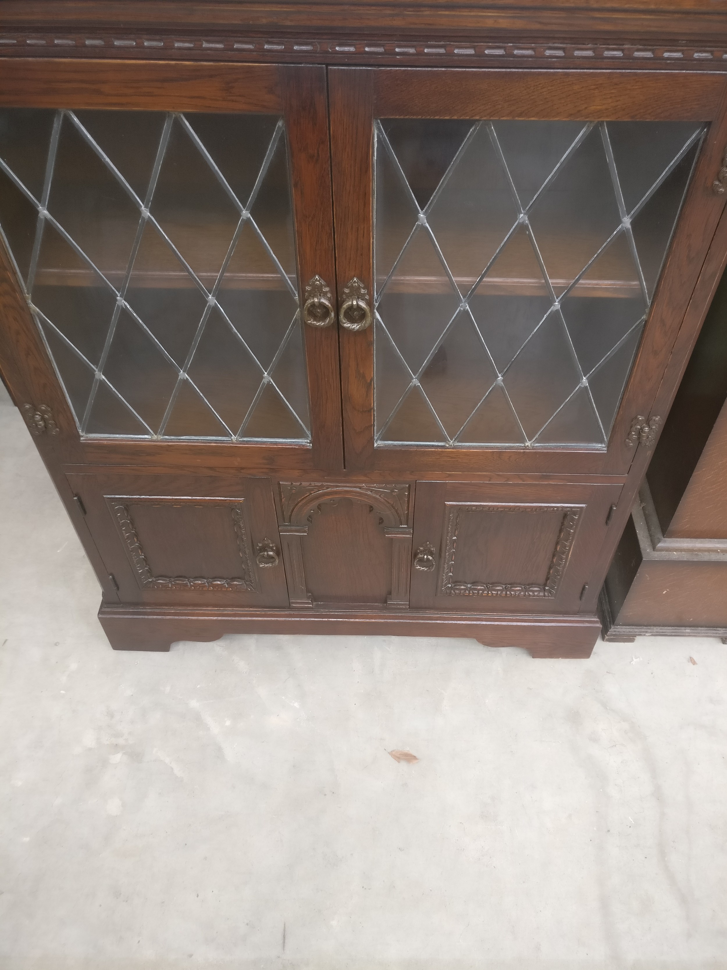 A small vintage carved oak bookcase with lead glazed doors and lower cupboards