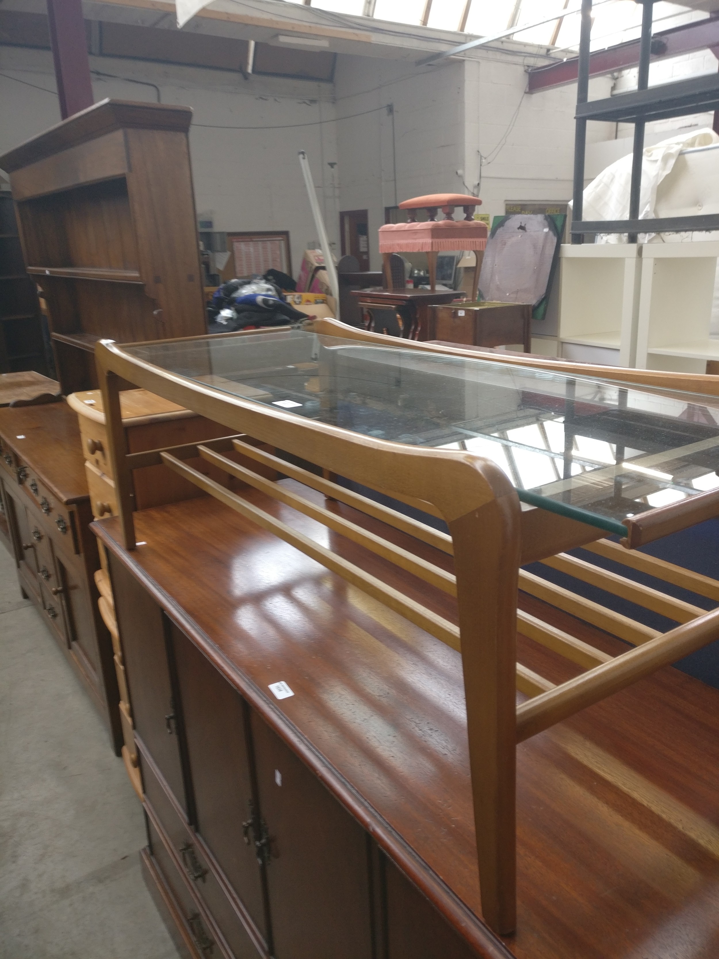 A retro glass topped coffee table with lower magazine rack