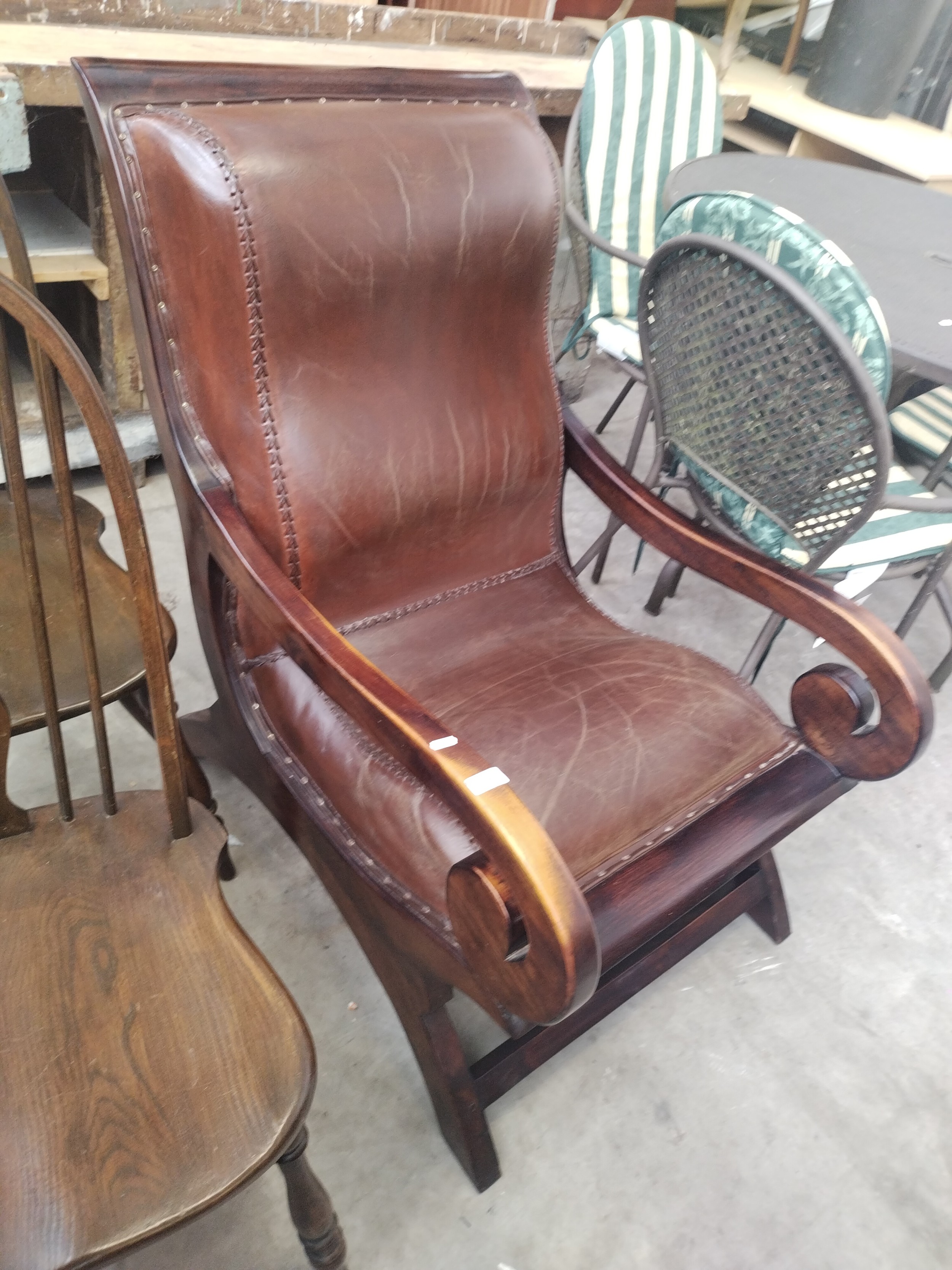 A large vintage hardwood framed lounger armchair with padded leather seat