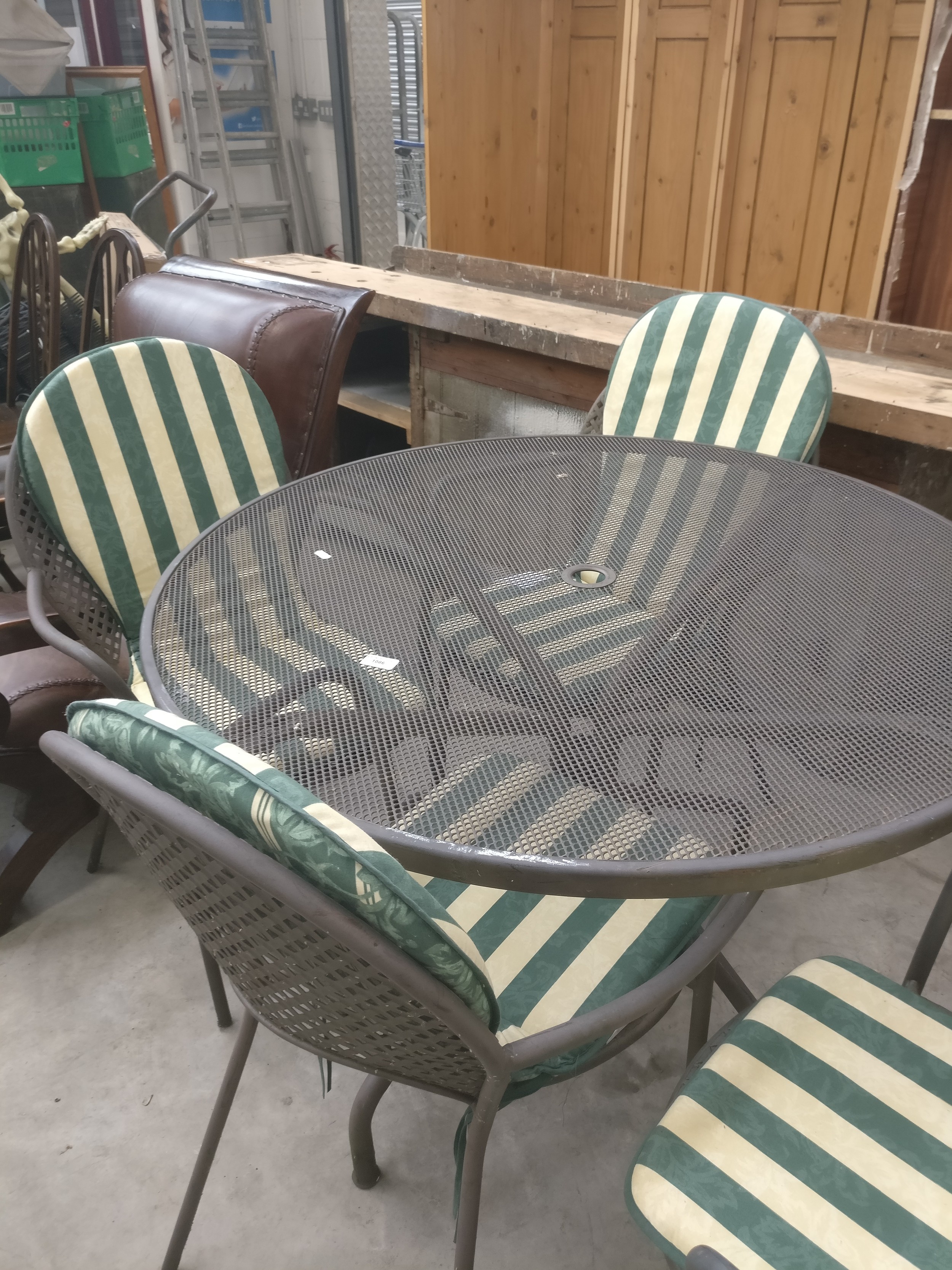 A large circular metal patio table with 4 x chairs and cushions