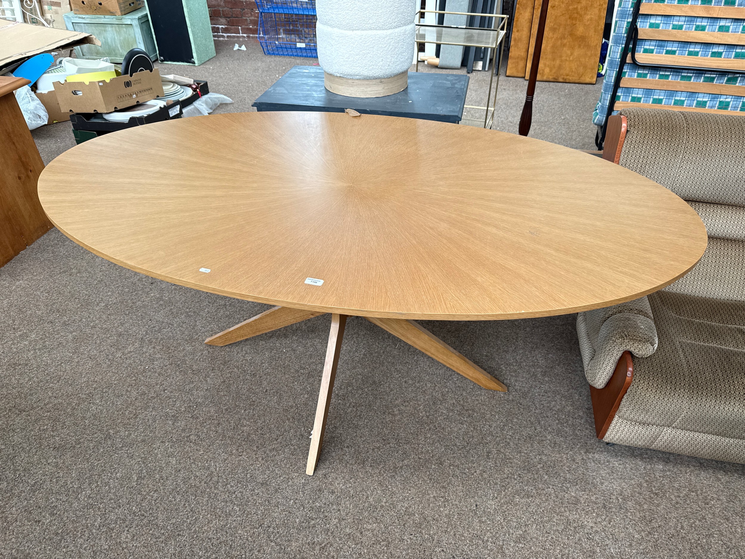 A large oval light oak pedestal dining table