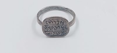 טבעת קמע מכסף, חתום, עם הכיתוב " אברהם יצחק יעקב משה ואהרון". מידות הקמע: 20X20 מ"מ.