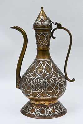 קנקן פליז יהודית דמשקאית עם מכסה 
קערת פליז דמשקאית עם מכסה מחובר בציר. משובצת כסף בטכניקת 