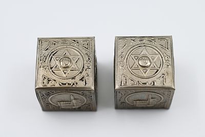 זוג כיסוי תפילין מצופים כסף - בצלאל. 
עיטורי מקומות קדושים ומגני דוד. 
חתום בצלאל ירושלם, 