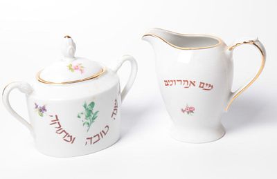 זוג פריטים בקבוצה. עשויים פורצלן יהודי. גרמניה. אמצע המאה ה20. קנקן למים אחרונים. וכלי לאחסון 