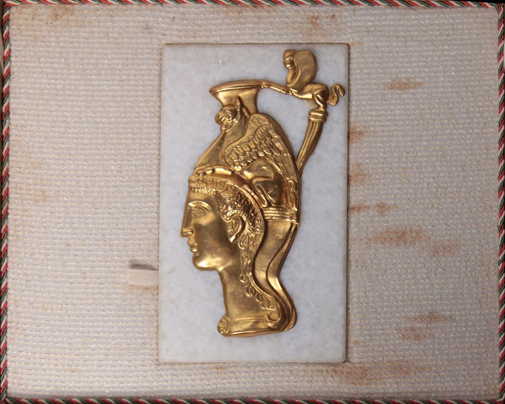 A box made of leather with a gold relief of a pharaonic figure on a marble base. The dimensions 