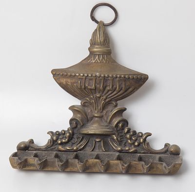 חנוכייה עשוייה ברונזה, בסגנון איטלקי , גב החנוכייה מעוטר בכד השמן עם להבה בכיתוב "חנוכה" 