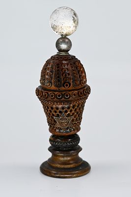 בשמים עץ בשילוב כסף, ארץ ישראל, 1900 בקירוב. 
בשמים עץ בשילוב כסף נפתח ההברגה בעבודת יד, מעוטר 