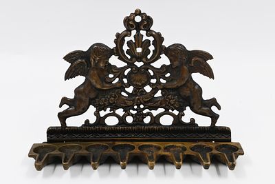 מנורת חנוכה עם עיטורי מלאכים – איטליה, המאה ה-18-19 
.הדופן האחורית בעלת צורה משולשת וכוללת 