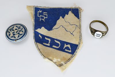 קבוצה טבעת סיכה ותג בד, הטבעת עם אמייל לבן עם עיטורים ואמצע כיתוב מכבי 1935, קוטר 2 ס'. 
הסיכה: 