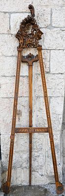 Wooden easel 
20th century. Sculpted at the top with an asymmetrical motif pattern. Height: 205 