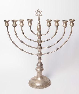 חנוכיית כסף פרסית, ראשית המאה ה-20. מעוטרת עבודת חריטה עם מוטיבים צמחיים. גובה: 30 ס"מ. משקל: 