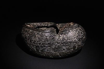An Islamic Kashkul Beggar's Bowl with Calligraphic and Floral Engravings. A dark-toned Kashkul 