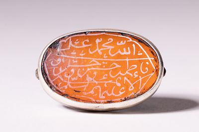 AN ISLAMIC SILVER ENGRAVED CARNELIAN TALISMANIC RING. A silver-mounted seal ring featuring an 