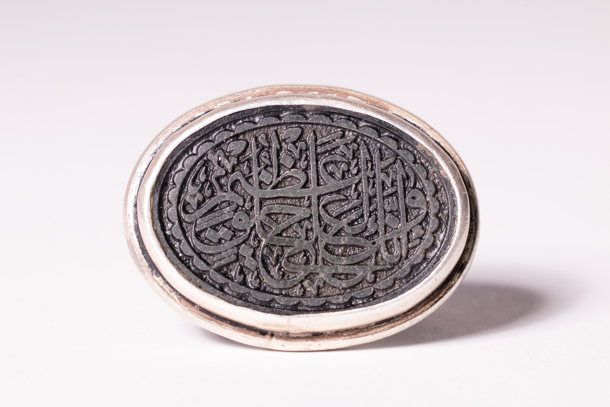 AN ISLAMIC SILVER AND INLAID STONE SIGNET SEAL RING.