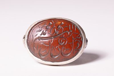 AN ISLAMIC SILVER AND INTAGLIO CARNELIAN SEAL RING. A Middle Eastern signet-style seal ring 
