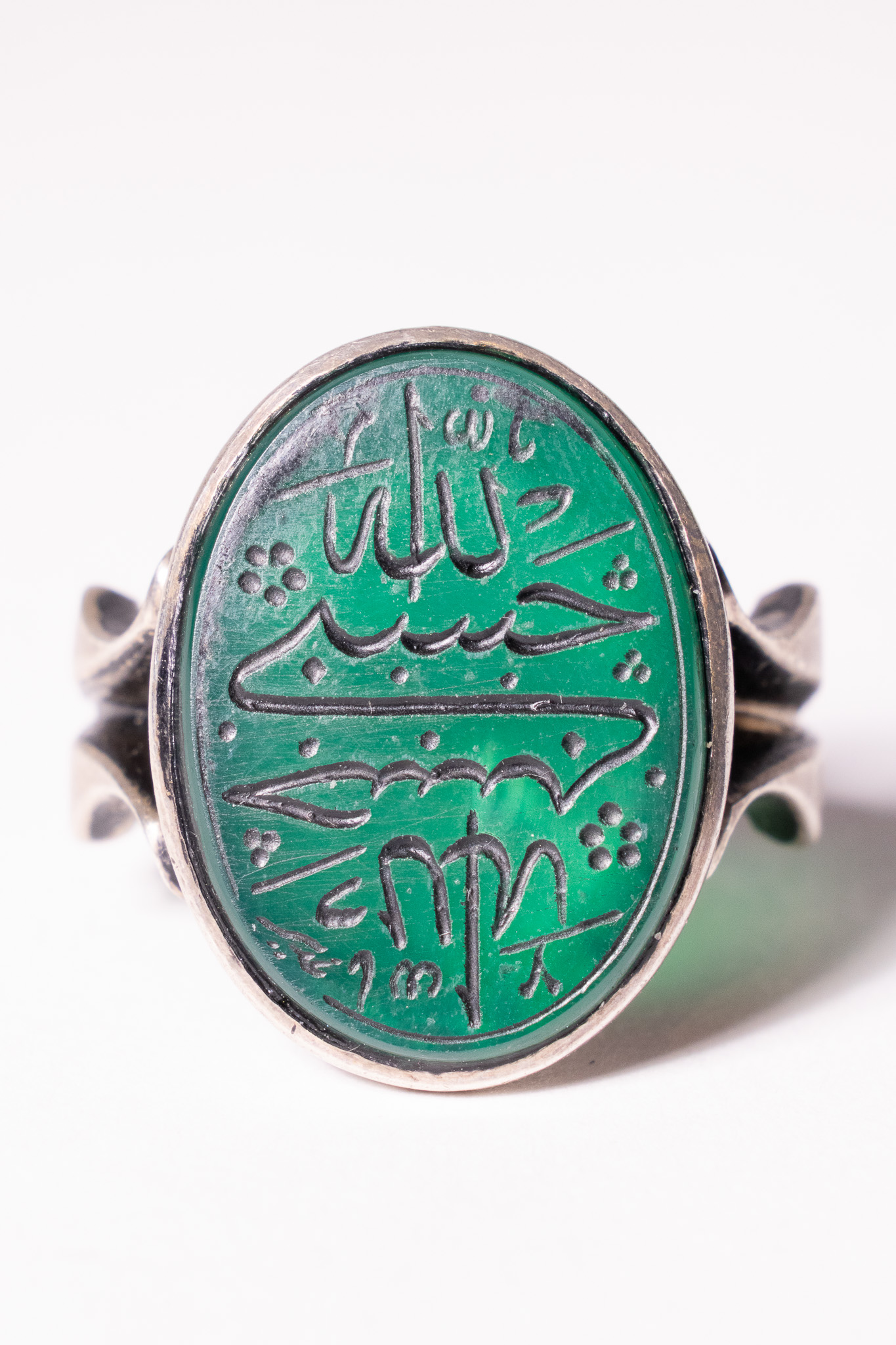 AN ISLAMIC SILVER AND ENGRAVED GREEN AGATE TALISMANIC SIGNET RING.