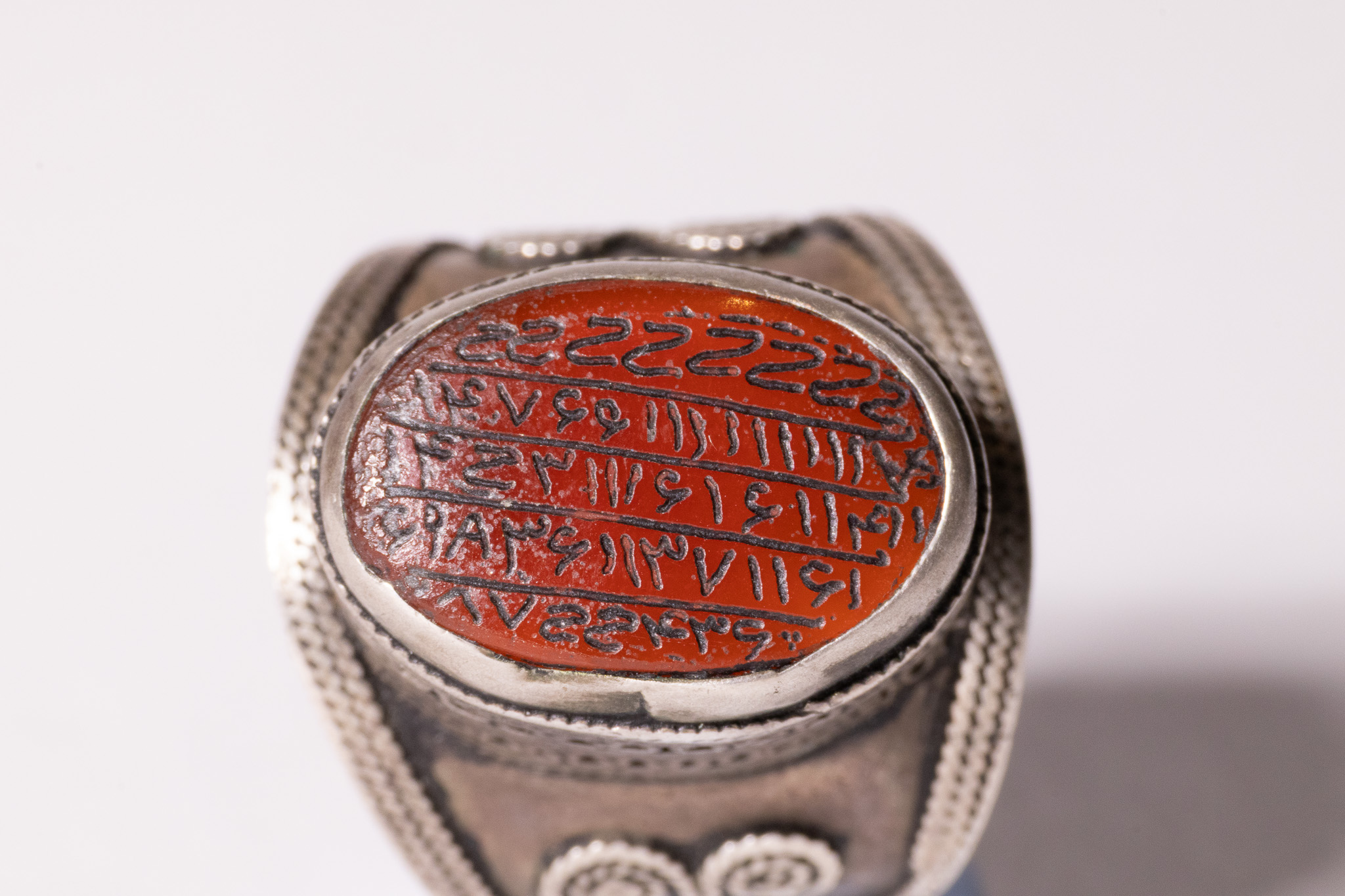 AN ISLAMIC TALISMANIC SILVER AND CARNELIAN SIGNET RING.