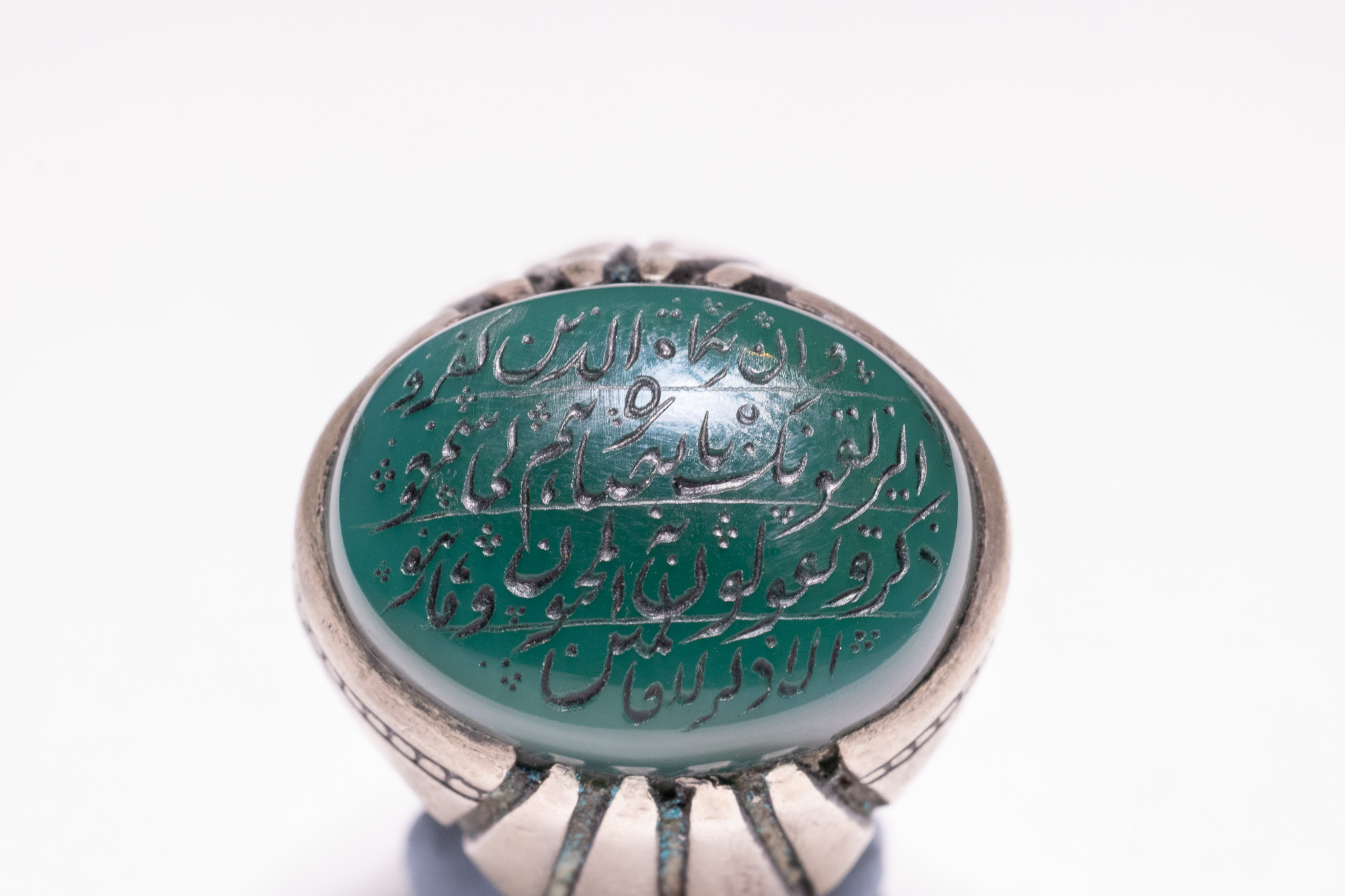 AN ISLAMIC SILVER TALISMANIC RING WITH ENGRAVED GREEN AGATE.