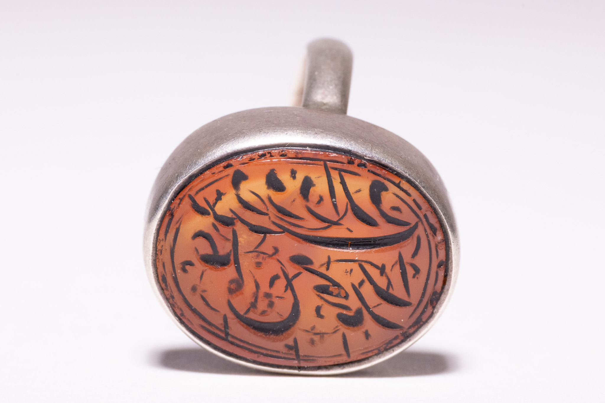 AN ISLAMIC SILVER AND CARNELIAN INTAGLIO SIGNET RING.