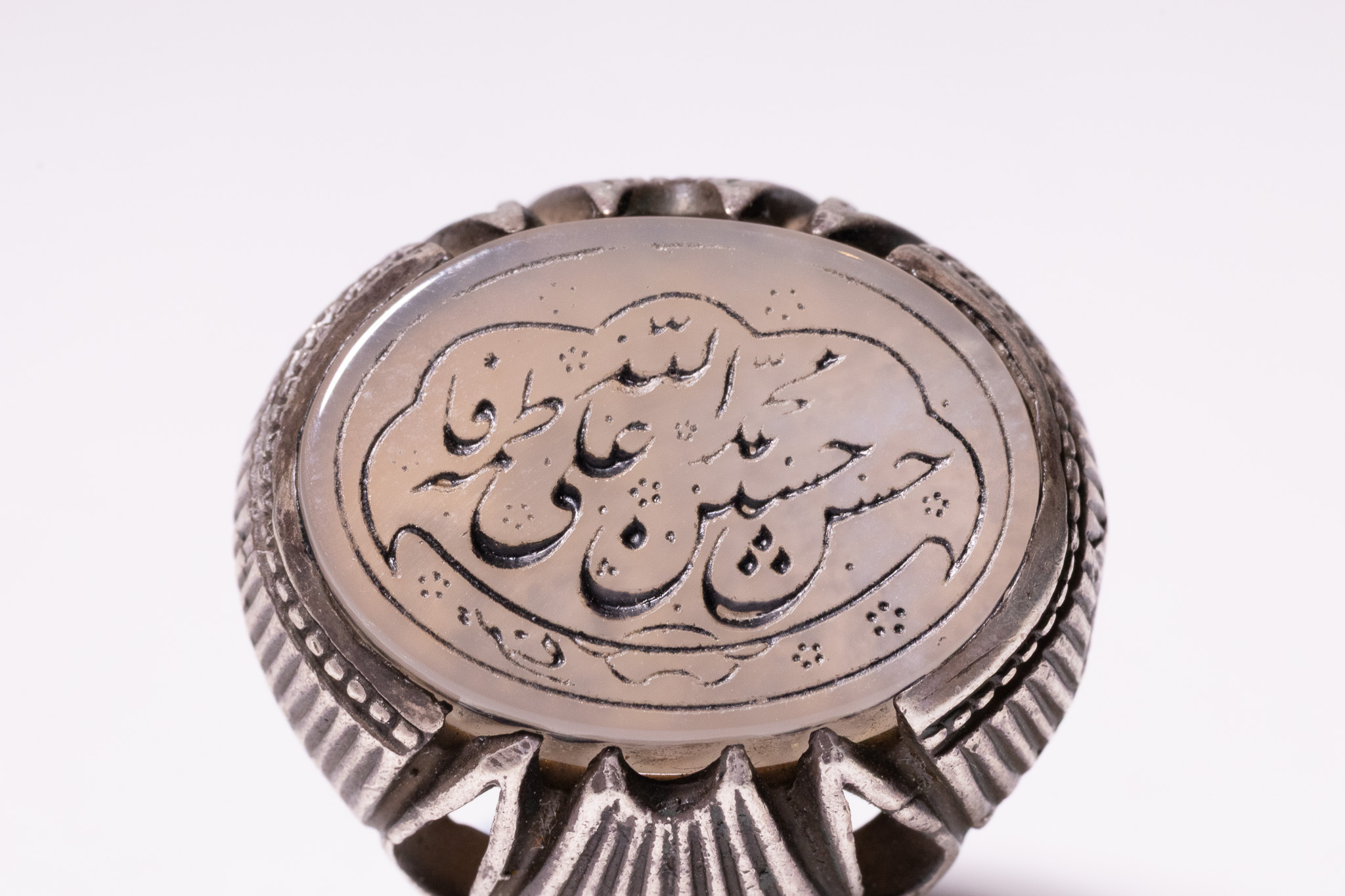 AN ISLAMIC SILVER SIGNET RING FEATURING AN ENGRAVED AGATE PLAQUE WITH CALLIGRAPHIC INSCRIPTION.
