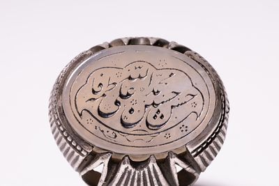 AN ISLAMIC SILVER SIGNET RING FEATURING AN ENGRAVED AGATE PLAQUE WITH CALLIGRAPHIC INSCRIPTION. 