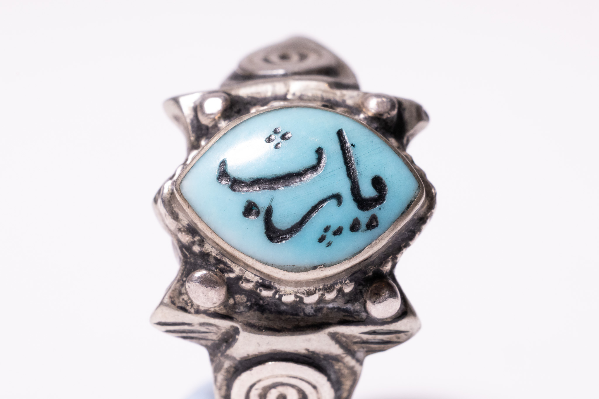 AN ISLAMIC SILVER RING WITH TURQUOISE INSCRIBED CABOCHON.