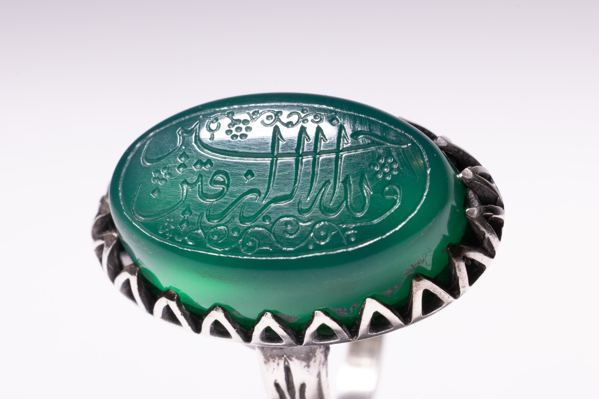 AN ISLAMIC SILVER TALISMANIC SIGNET RING WITH INTAGLIO-ENGRAVED GREEN AGATE.