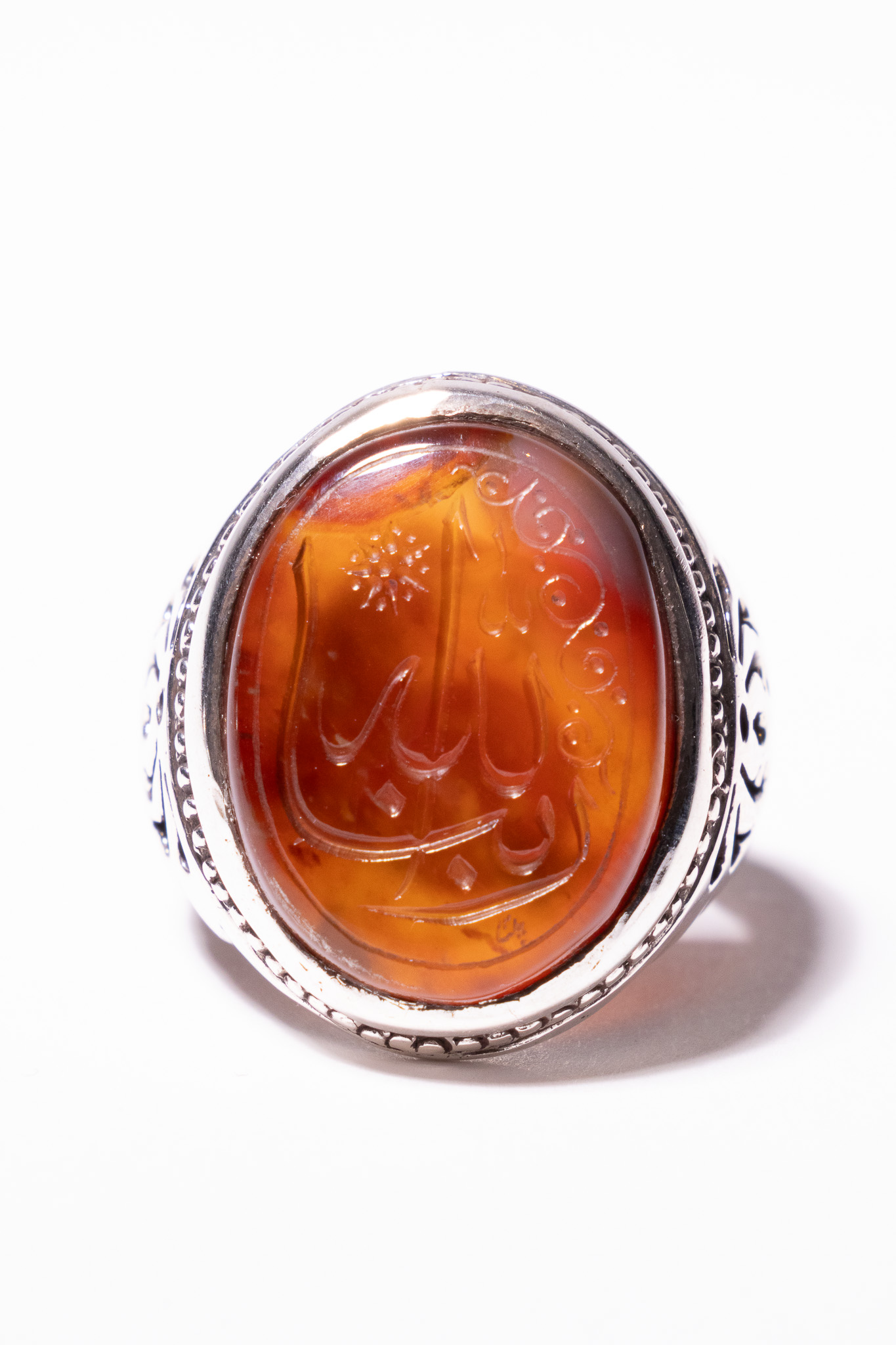 AN ISLAMIC YEMENI AQEEQ ENGRAVED CARNELIAN AND SILVER SIGNET RING.