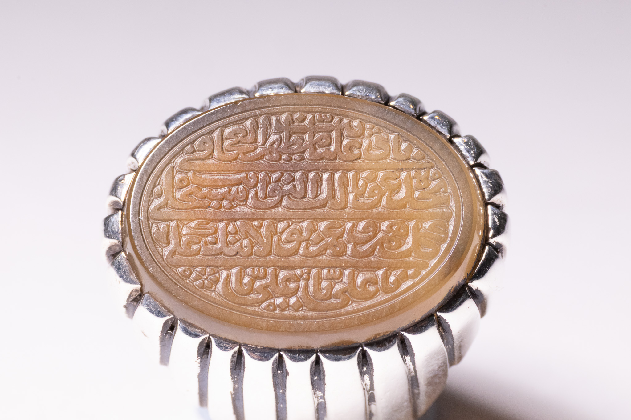 AN ISLAMIC CALLIGRAPHIC ENGRAVED AGATE AND SILVER SIGNET RING.