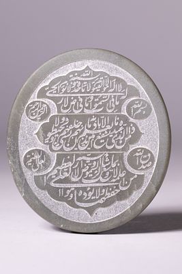 AN ISLAMIC TALISMANIC HEMITITE PLAQUE WITH QURANIC INSCRIPTIONS. A circular talismanic plaque 