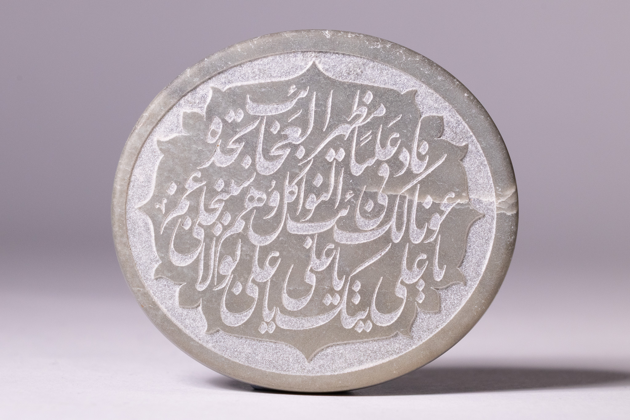 AN ISLAMIC CARVED HEMITITE CALLIGRAPHIC ROUNDEL WITH QURANIC INSCRIPTIONS.