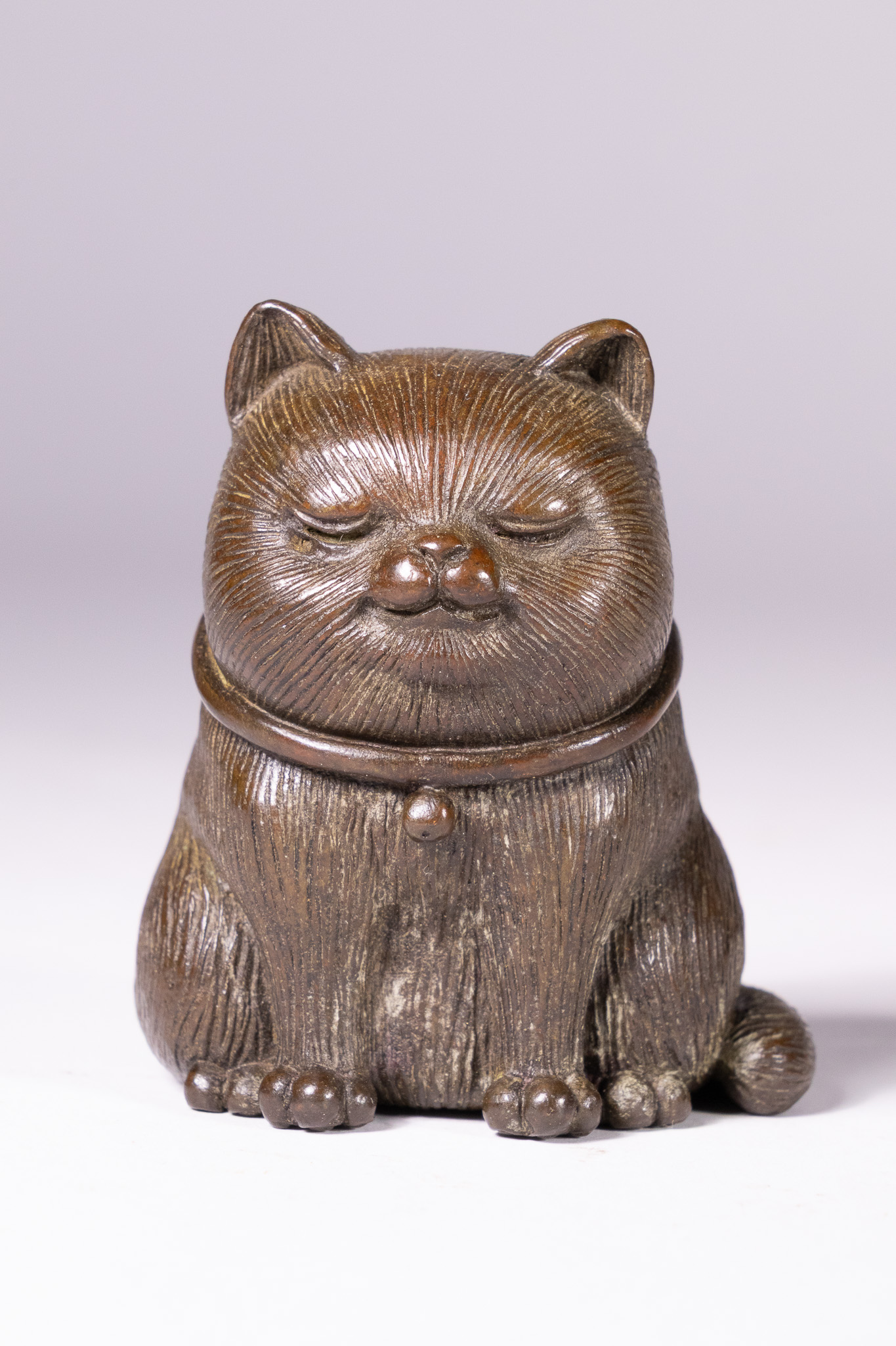 A JAPANESE PATINATED BRONZE OKIMONO OF A SEATED CAT.