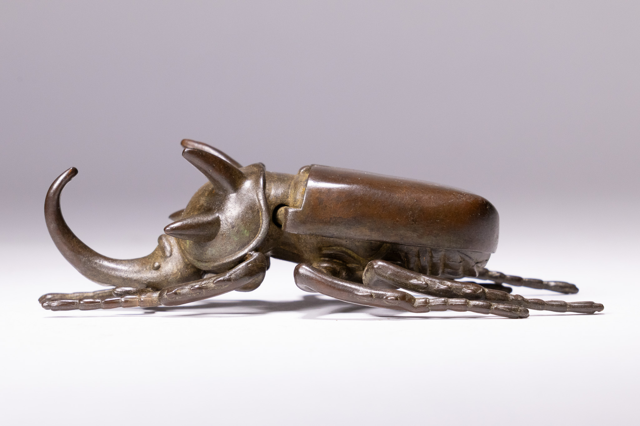 A JAPANESE PATINATED BRONZE ARTICULATED MODEL OF A RHINOCEROS BEETLE.