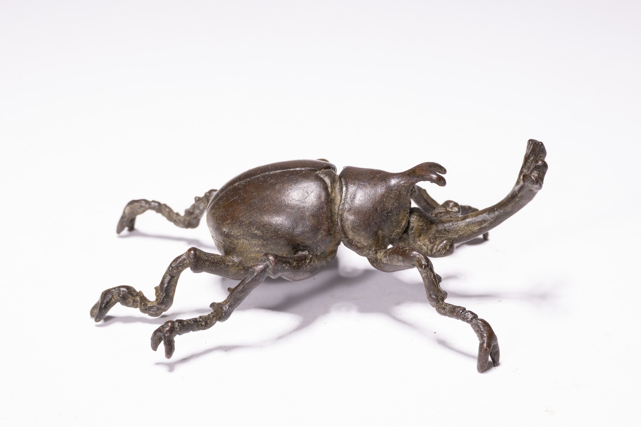 A JAPANESE MEIJI PERIOD BRONZE RHINOCEROS BEETLE OKIMONO.