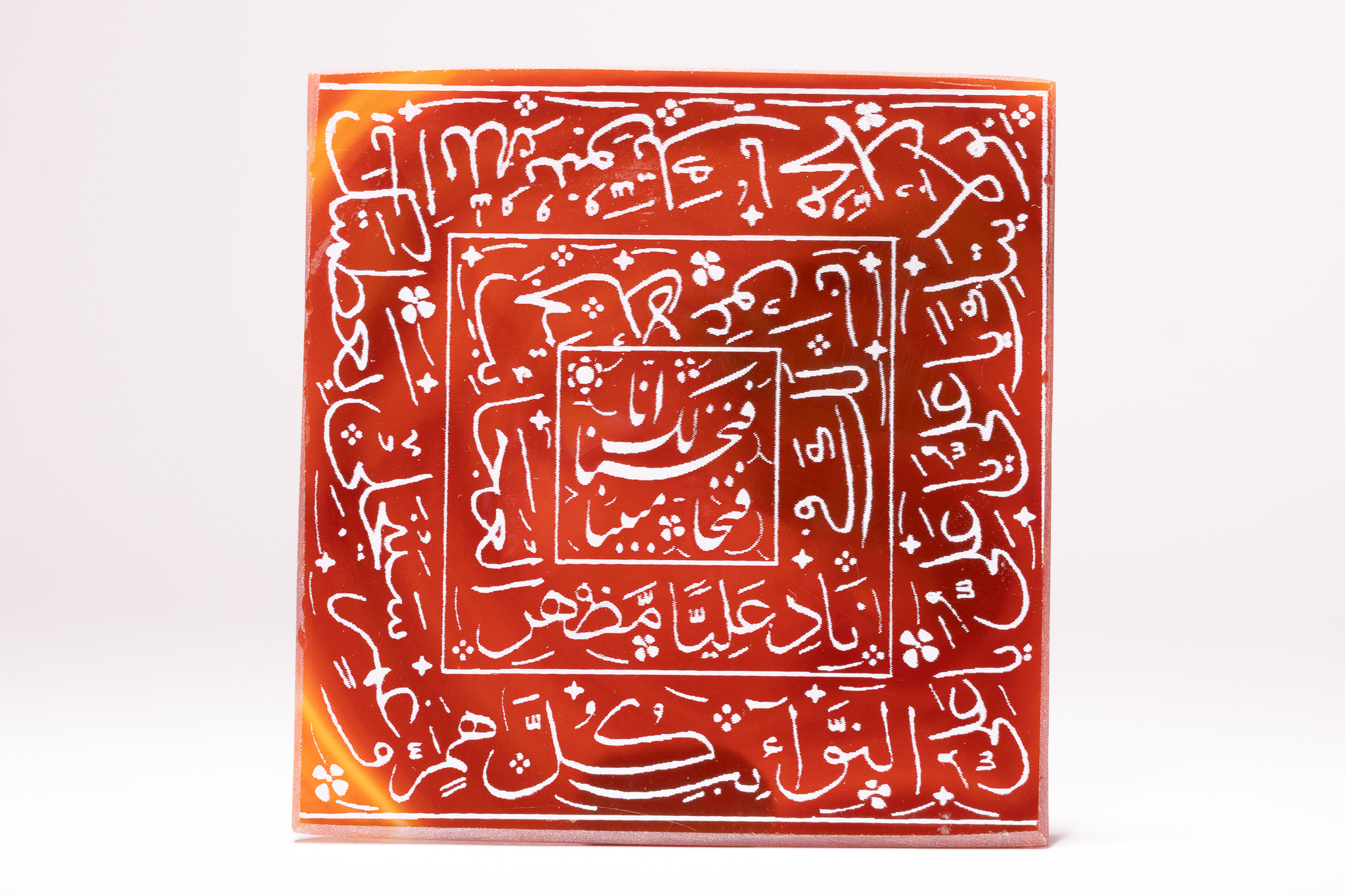 AN ISLAMIC SQUARE INSCRIBED CARNELIAN AMULET SEAL STONE WITH NAD-E ALI PRAYER.