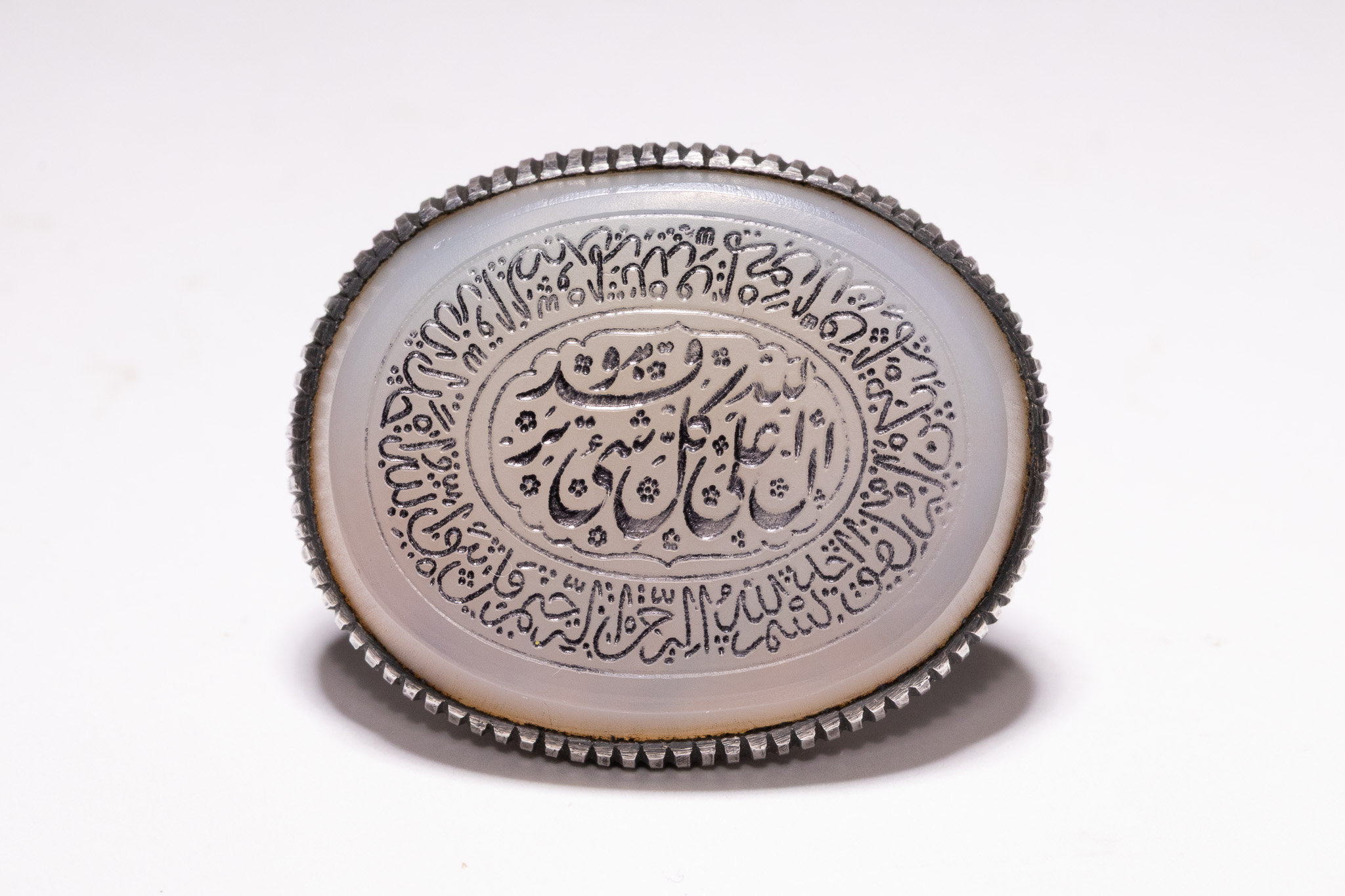 AN ISLAMIC WHITE METAL AND AGATE SIGNET RING.