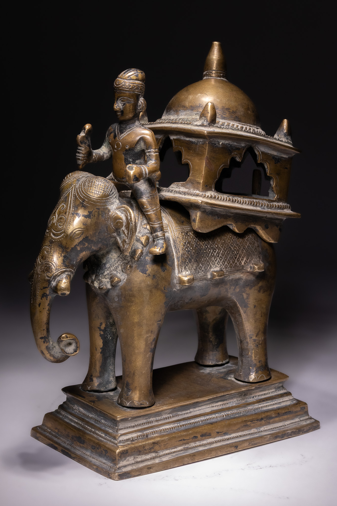 AN INDIAN CAST BRONZE MODEL OF A CEREMONIAL ELEPHANT WITH MAHOUT AND HOWDAH, 19TH-20TH CENTURY.