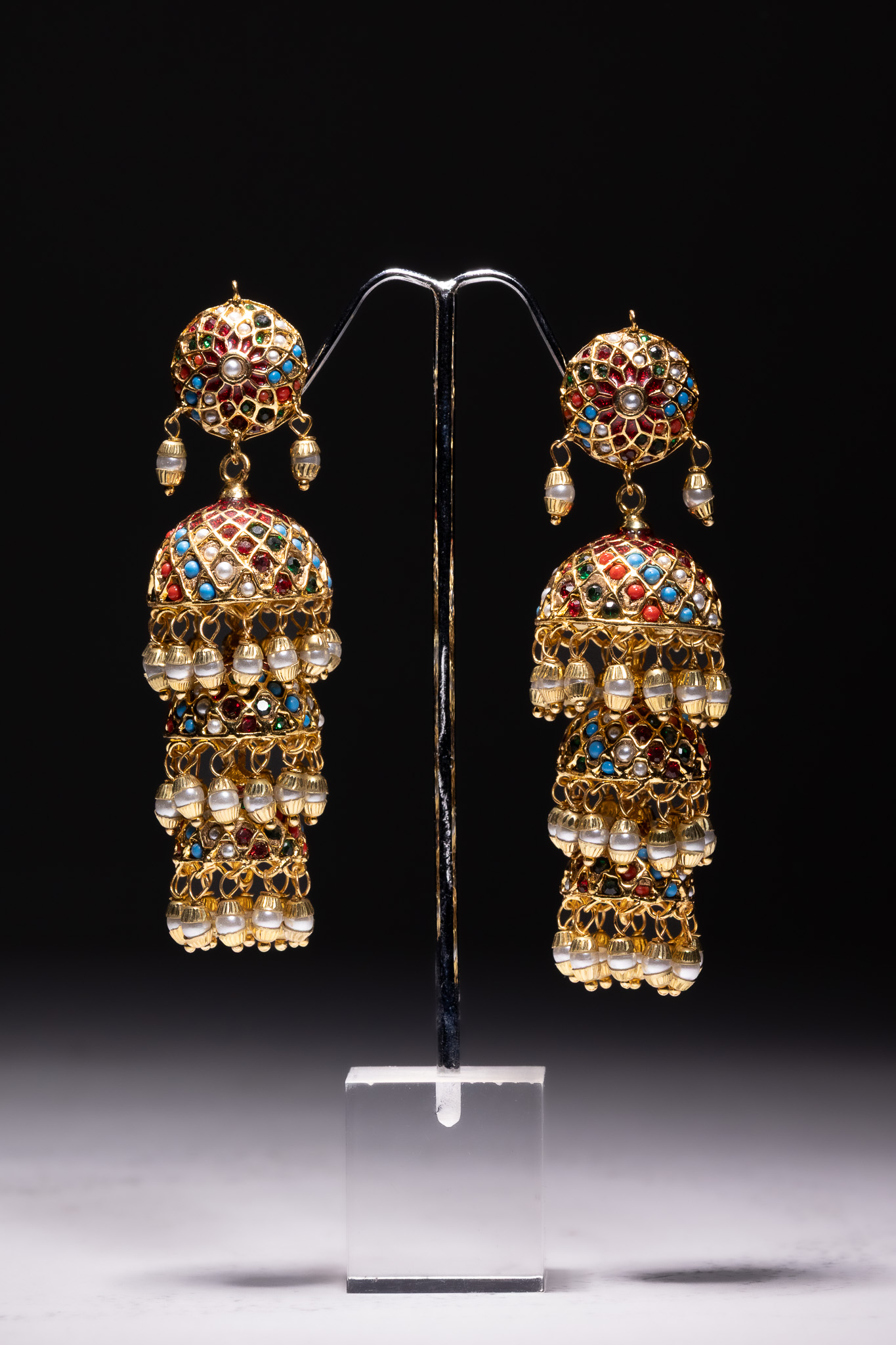 A PAIR OF MULTI-TIERED GOLD-TONED JHUMKA EARRINGS WITH COLOURED INLAYS AND FAUX-PEARLS.