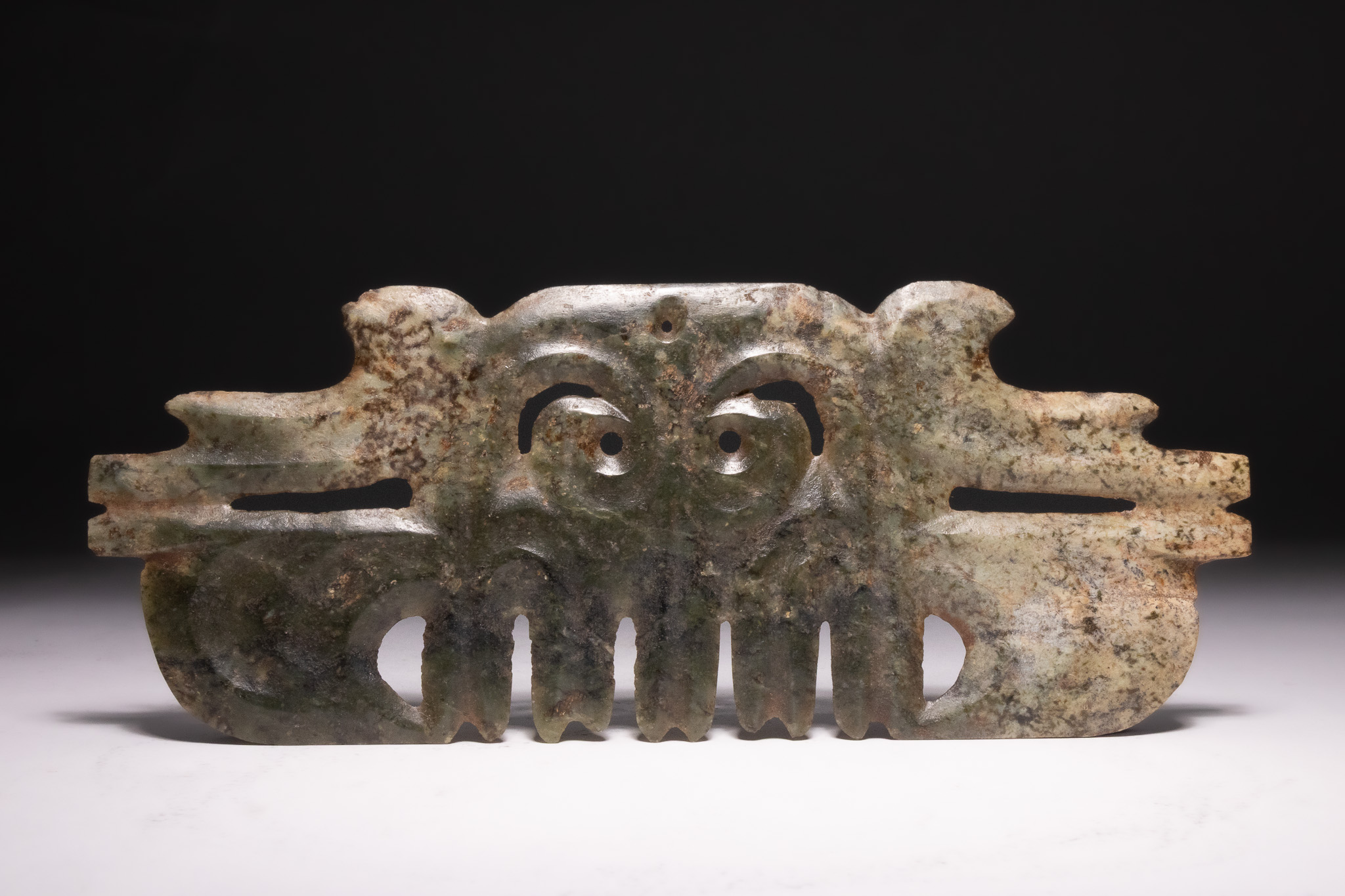 A HONGSHAN ARCHAIC MOTTLED JADE MASK PENDANT.