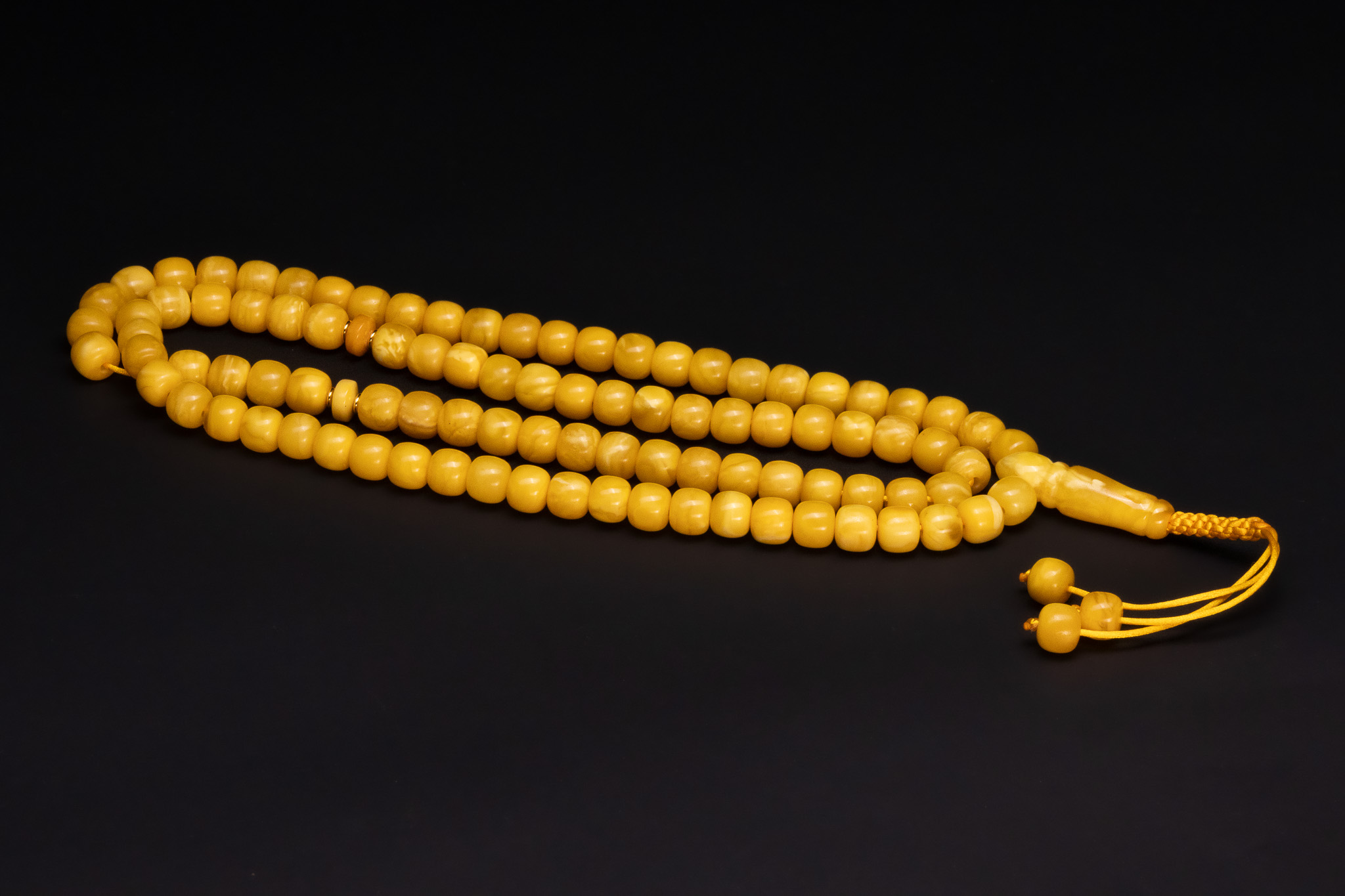 A STRAND OF BUTTERSCOTCH AMBER PRAYER BEADS WITH GOLD-TONED SPACERS.