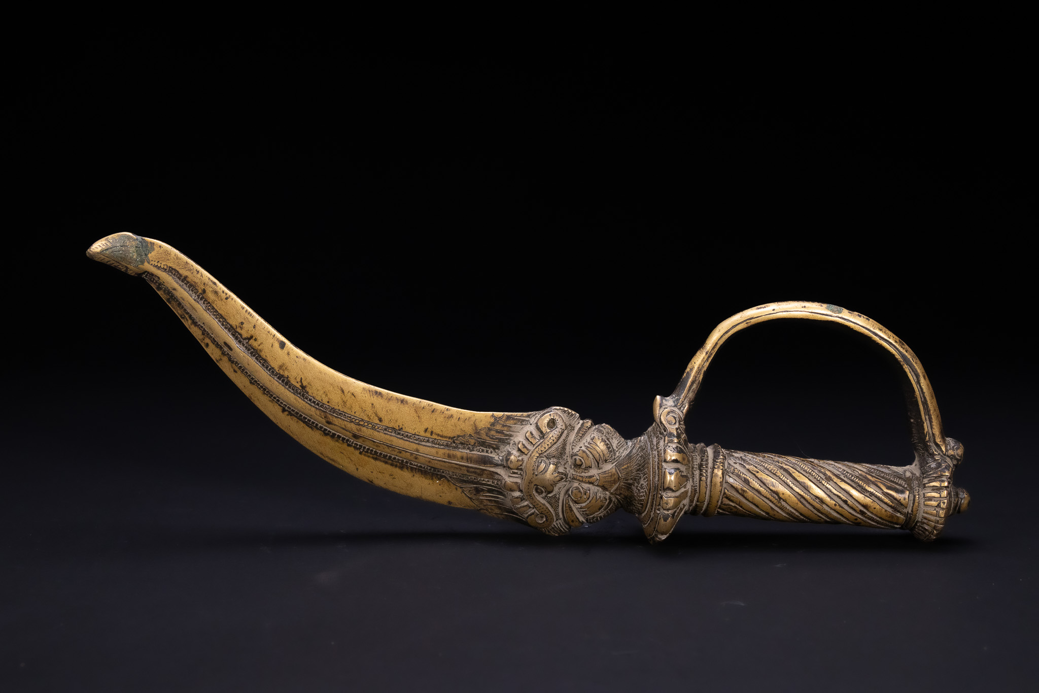 A SOUTH INDIAN BRASS CEREMONIAL DAGGER WITH KIRTIMUKHA MASK.