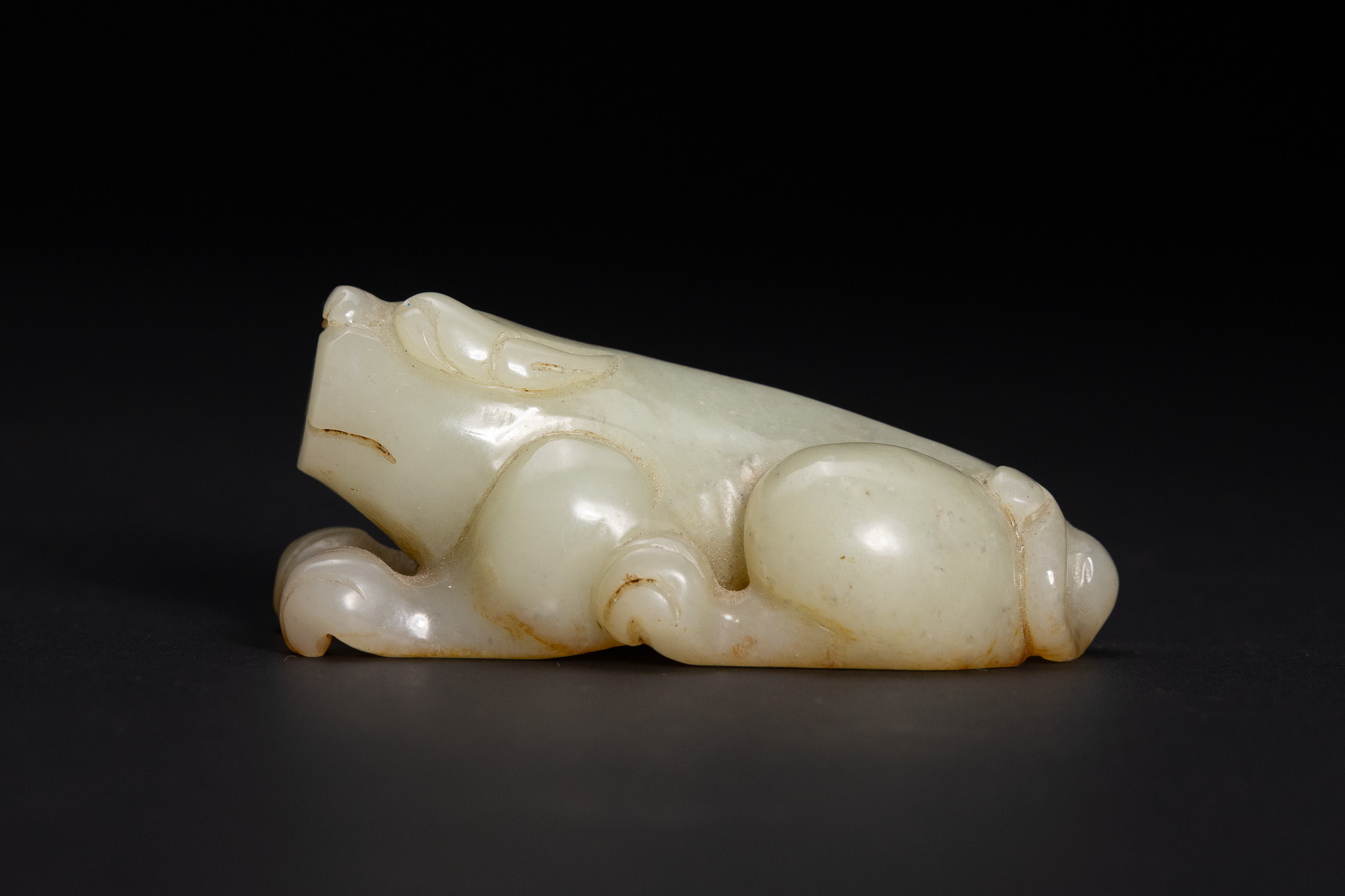 A CHINESE CARVED CELADON JADE MYTHICAL BEAST TOGGLE, BIXIE.