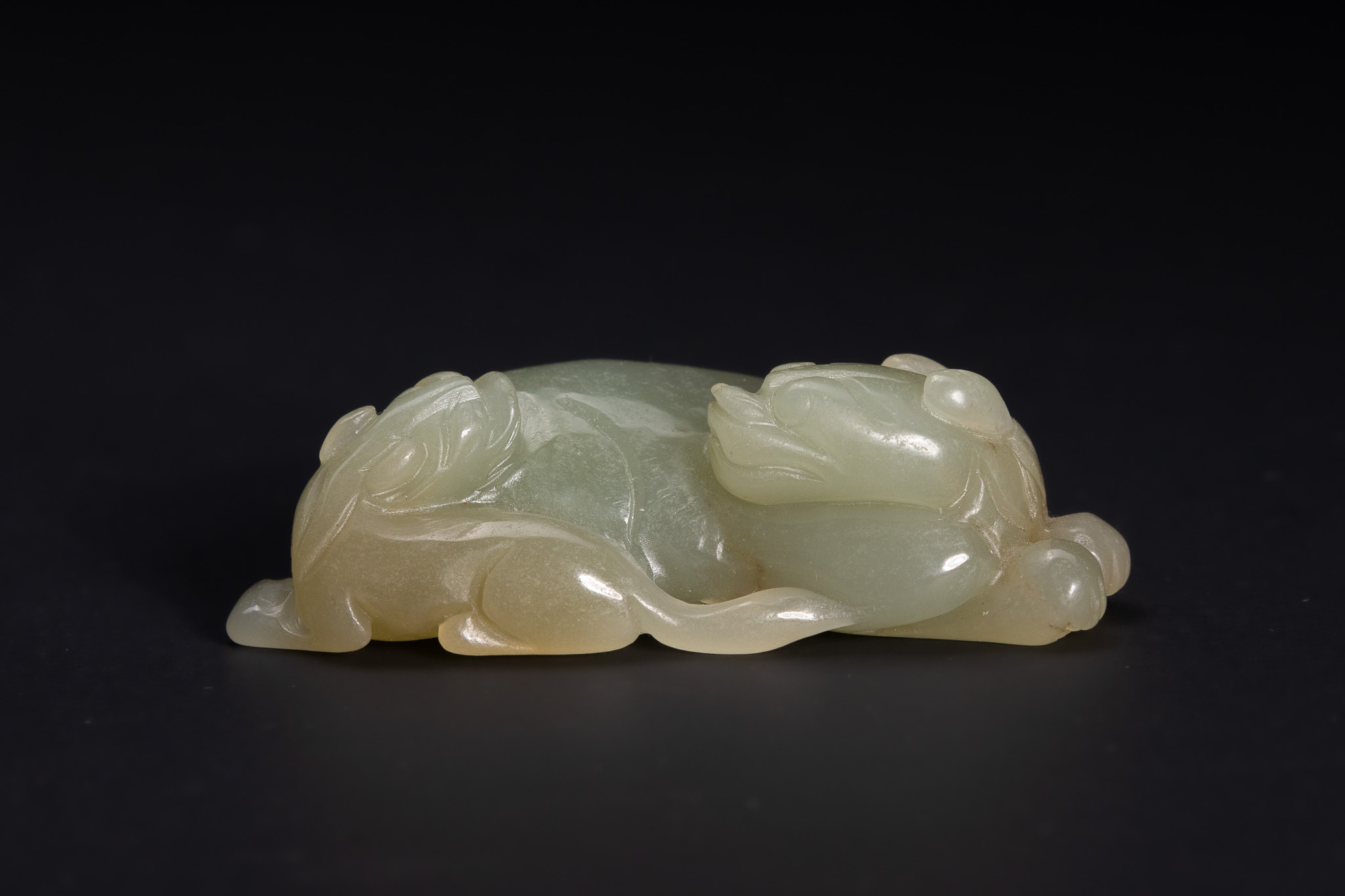 A CHINESE PALE CELADON JADE CARVING OF A RECUMBENT MYTHICAL BEAST.