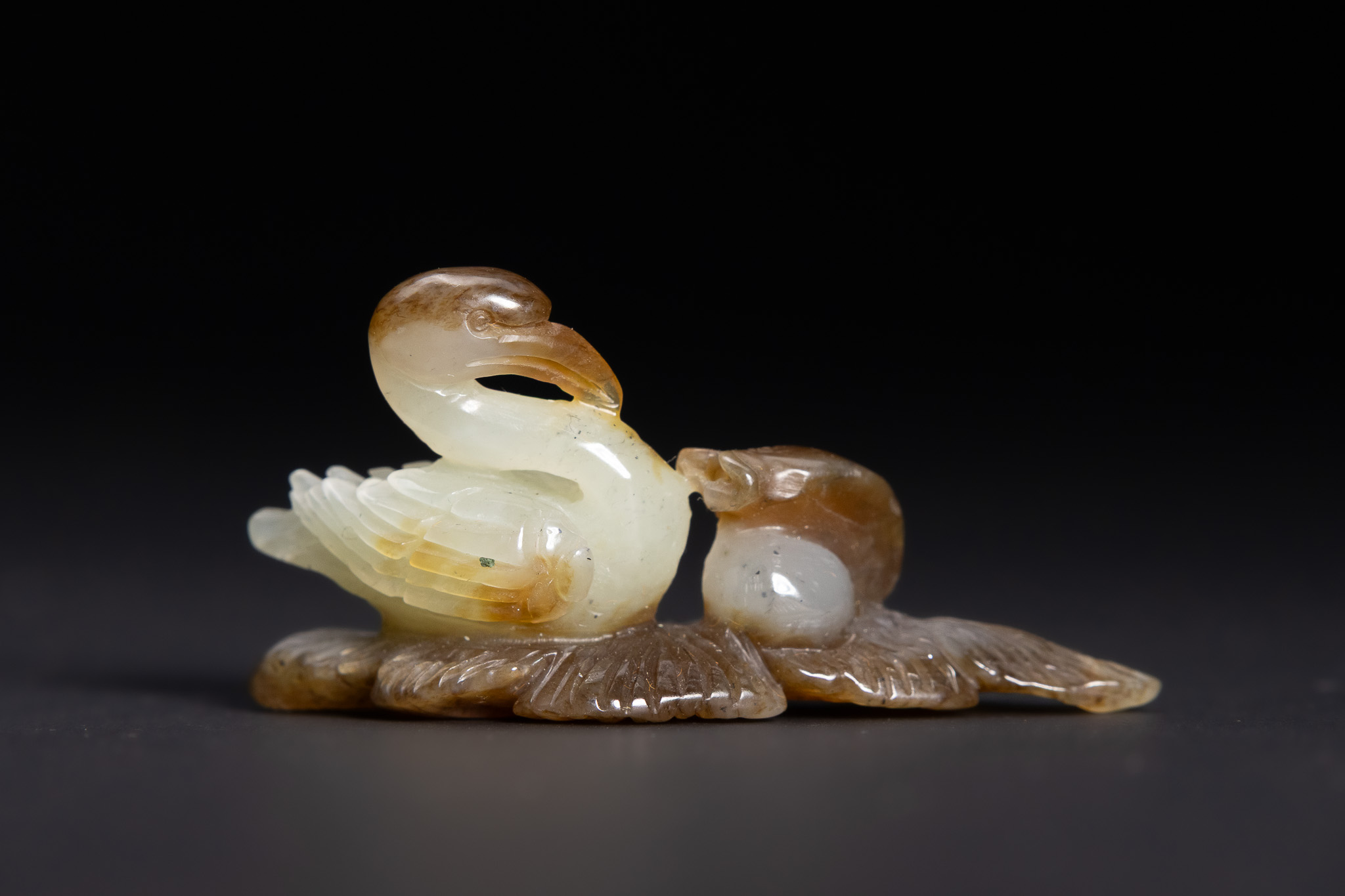 A CHINESE RUSSET AND CELADON JADE CARVING OF A GOOSE AND GOSLING.