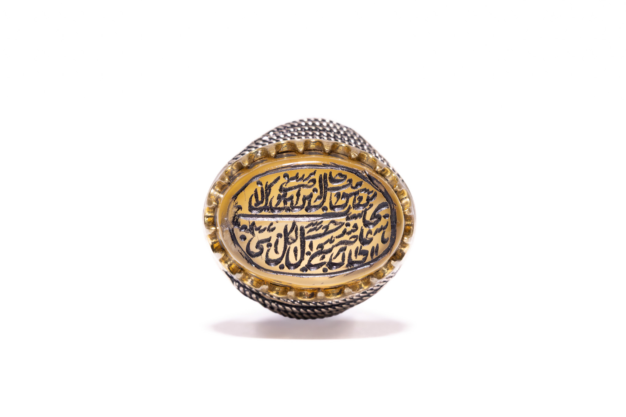 AN ISLAMIC TWO-TONE TALISMANIC SIGNET RING WITH ENGRAVED HONEY-COLOURED AGATE.